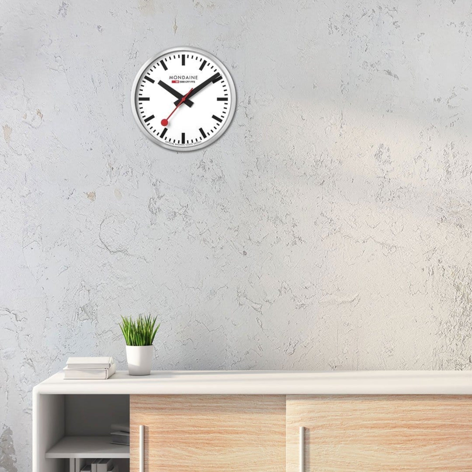 Mondaine silver wall clock A990.CLOCK.16SBB mounted over sideboard cabinet