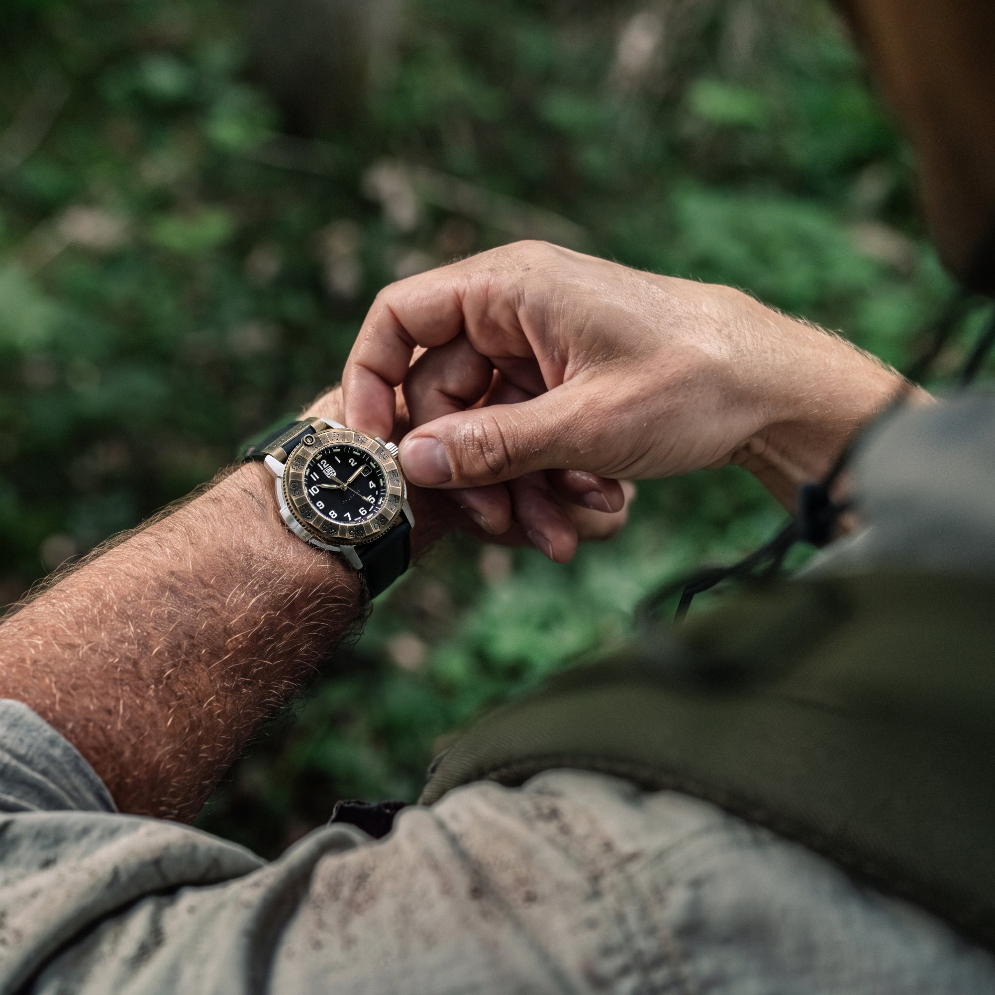 Close-up of a person adjusting the crown of the Luminox Adventure Watch XL.1301 on their wrist in a dark forest setting