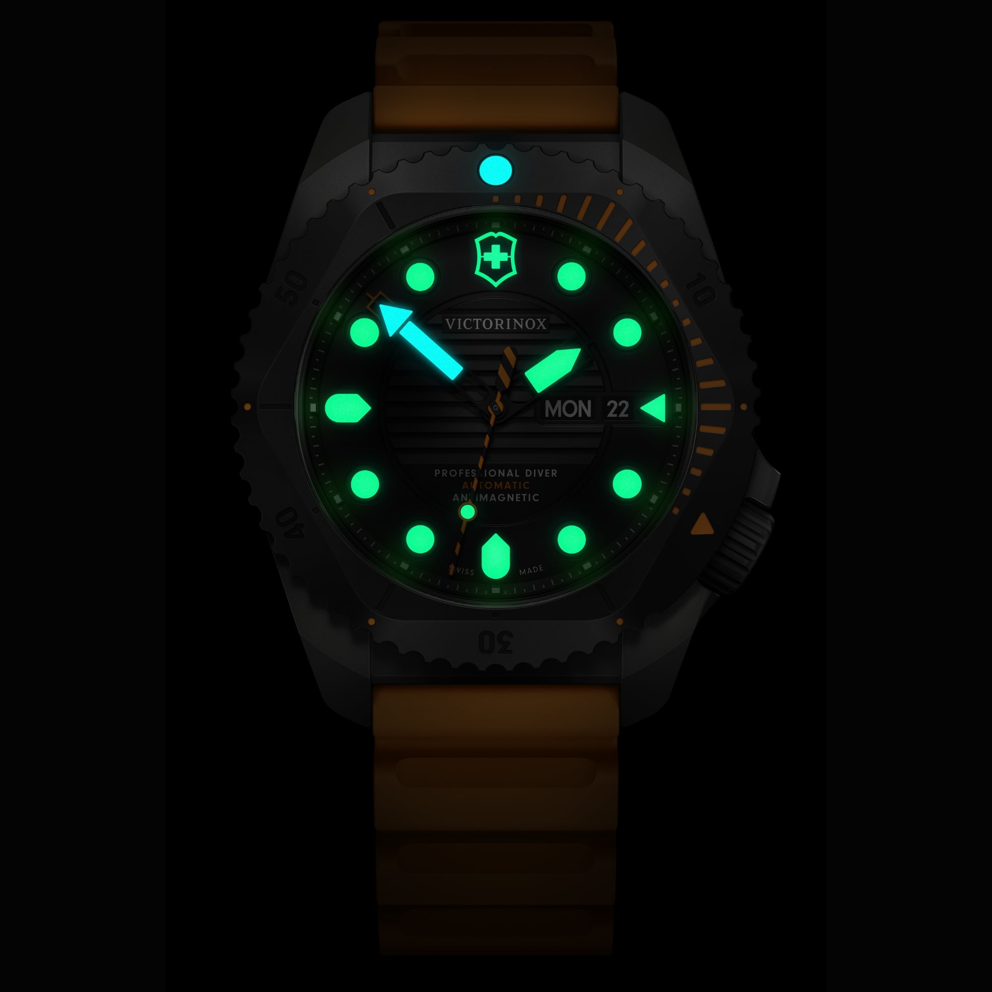 A dark close-up of a Victorinox Dive Pro 43mm watch featuring green and blue glowing lume and an orange strap.