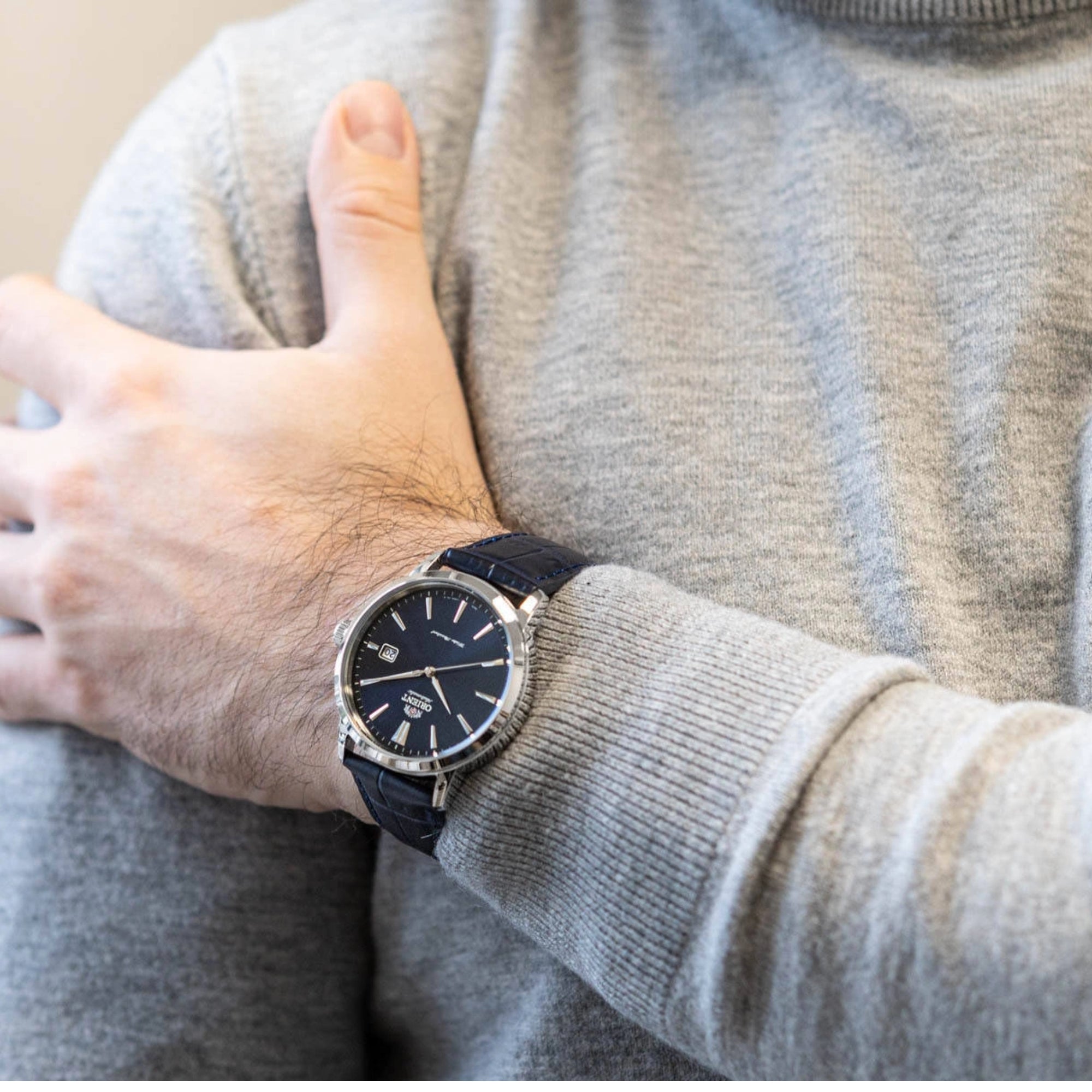 Wrist of a man wearing an Orient Contemporary watch with a blue dial and blue leather strap.