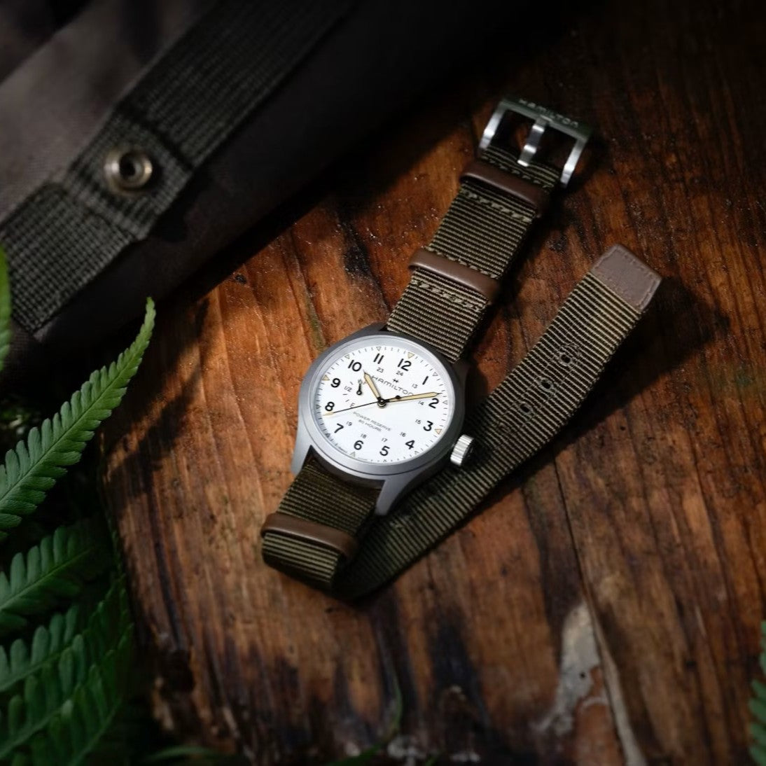 Hamilton Khaki Field Mechanical watch with white dial resting on dark rustic wood table