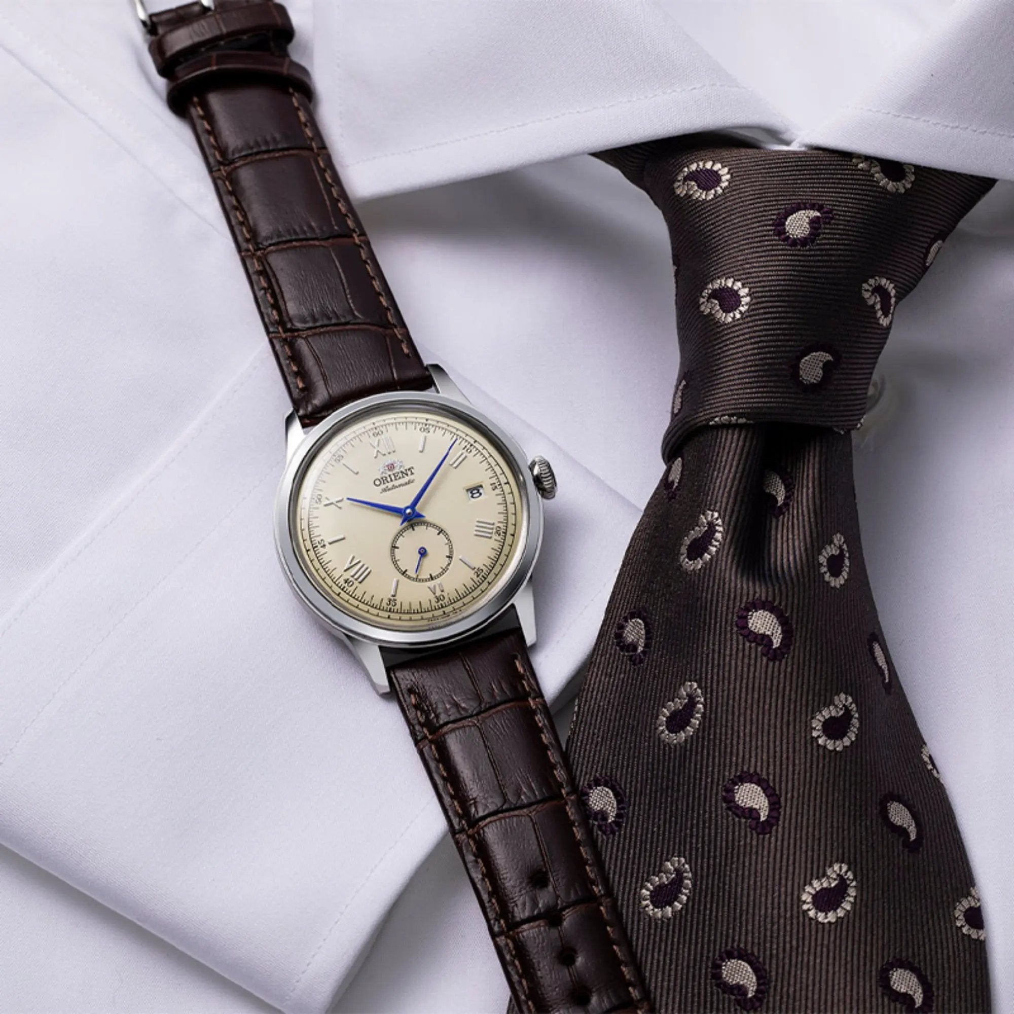Orient Bambino 38mm Small Seconds RA-AP0105Y30B leather watch laid flat on a white formal shirt next to a patterned tie