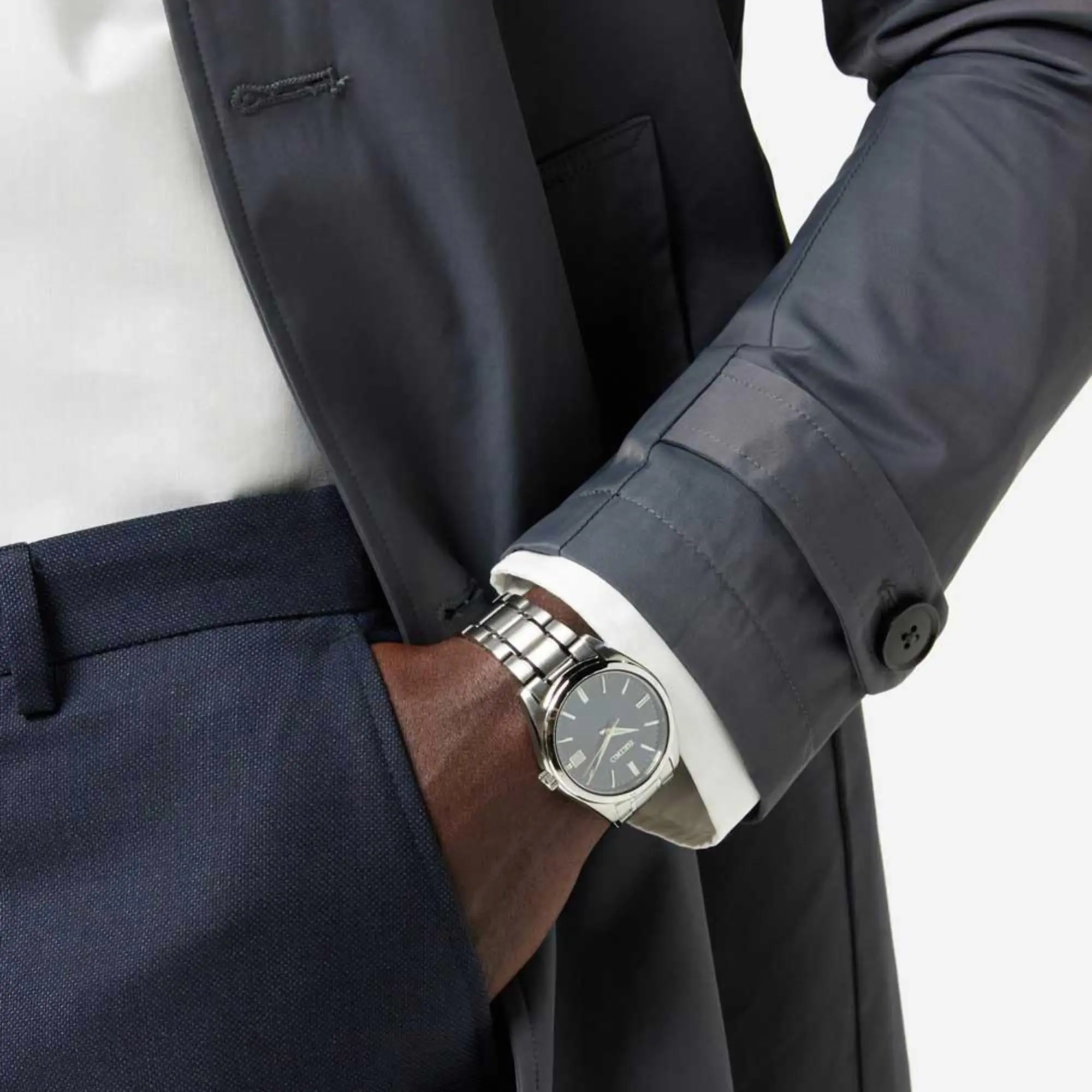 A person wearing the Seiko Essentials 40mm Blue Dial Steel Mens Quartz Watch paired with a dark trench coat jacket