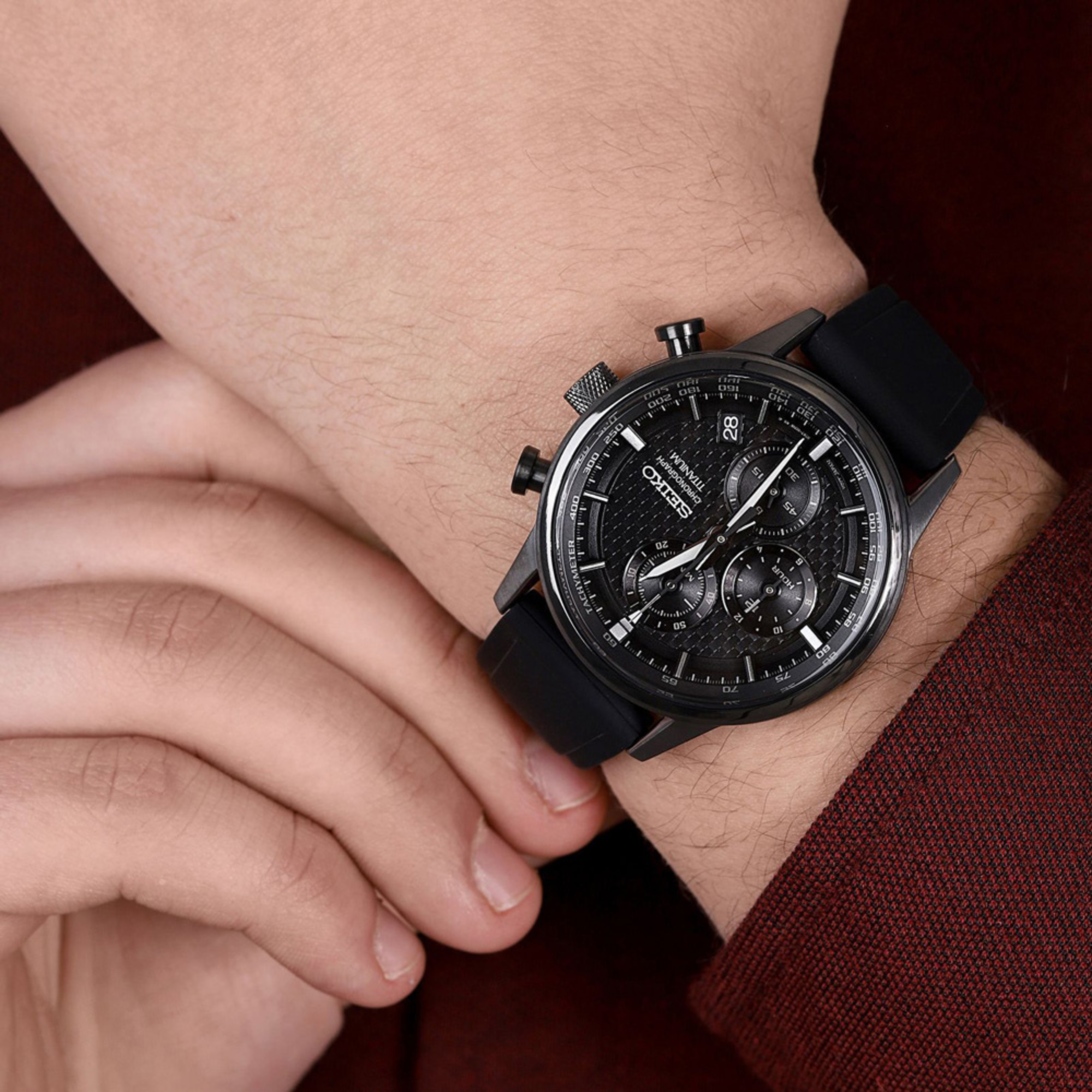 Black wristwatch on a person's wrist with a blurred background