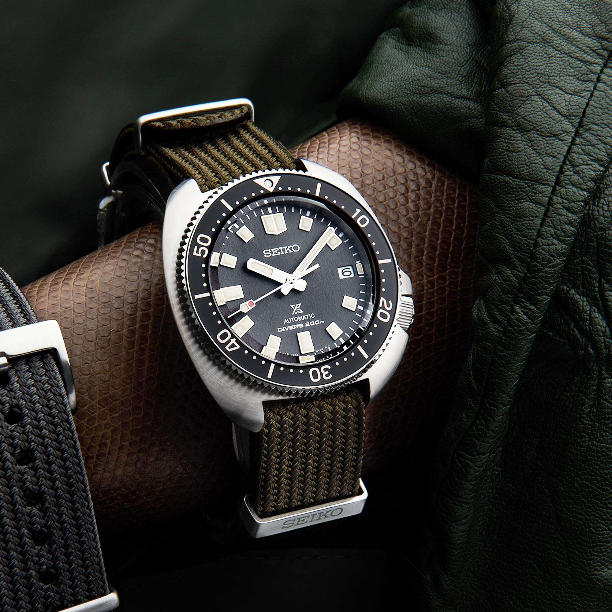 Seiko watch with brown strap on a wrist against a dark background