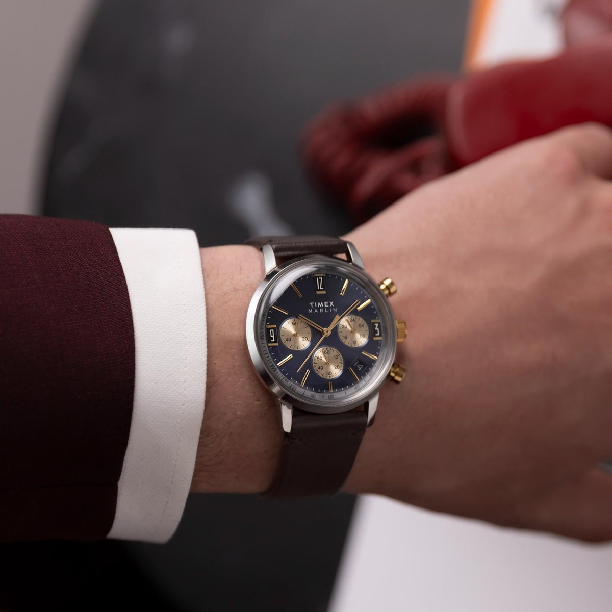 Timex chronograph on wrist, navy blue dial, brown leather strap, gold pushers