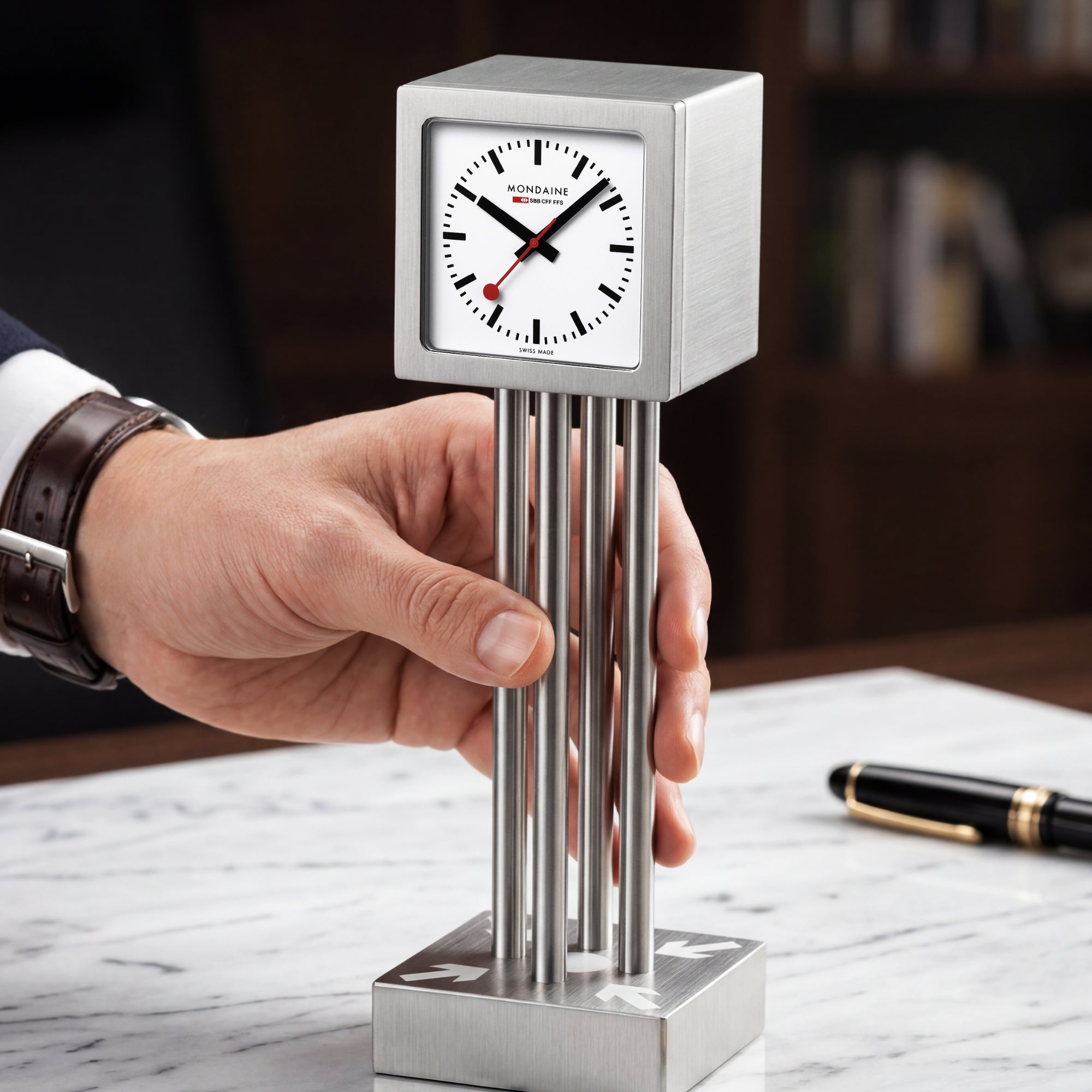Mini table clock on cylindrical base held by hand