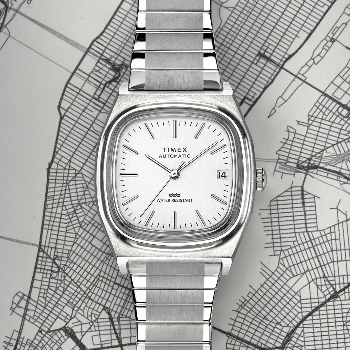 Timex Reissue 1983 E Line TW2W70800 flat lay view displaying silver dial face resting on map background