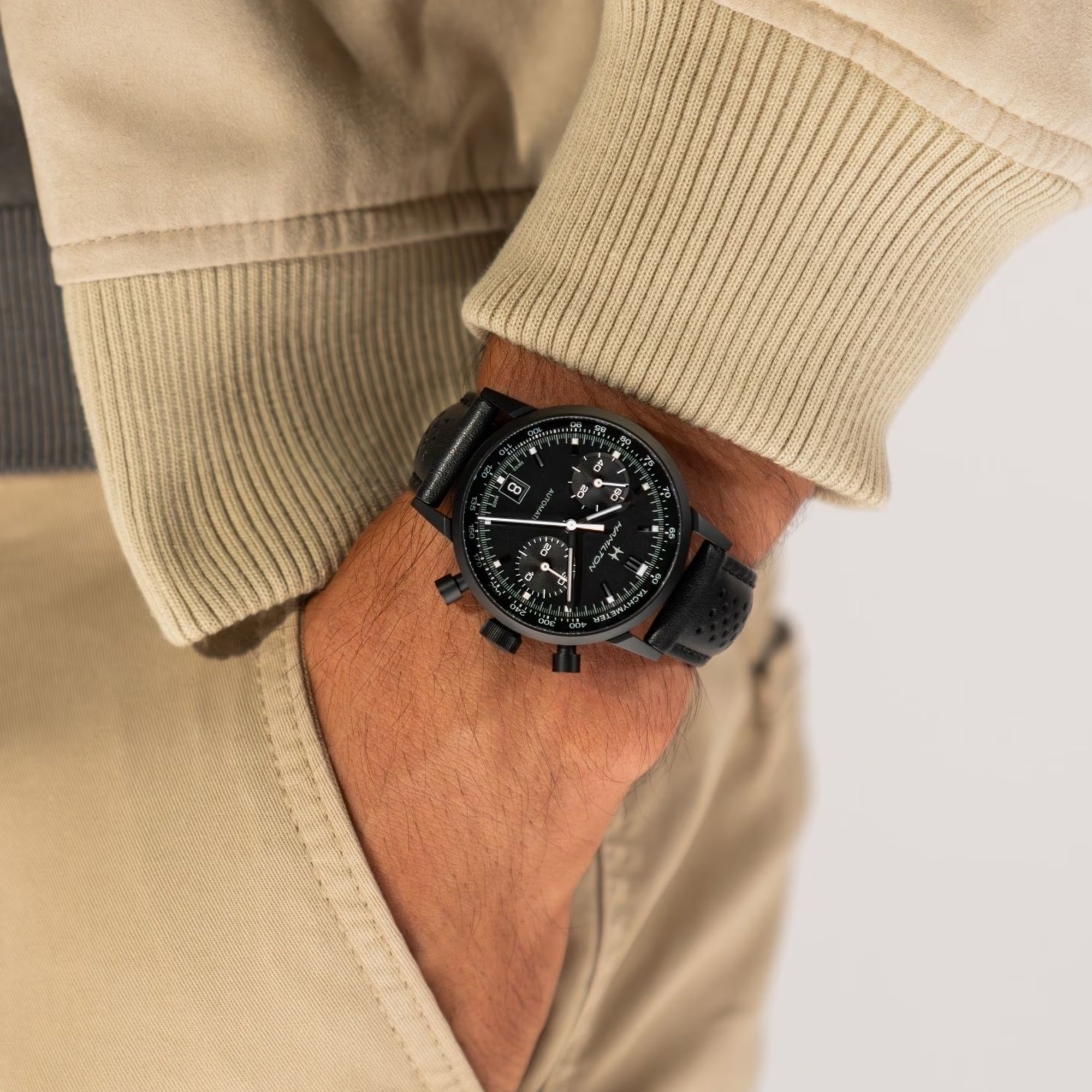 Mens wrist watch with black dial and black leather strap on a man's arm