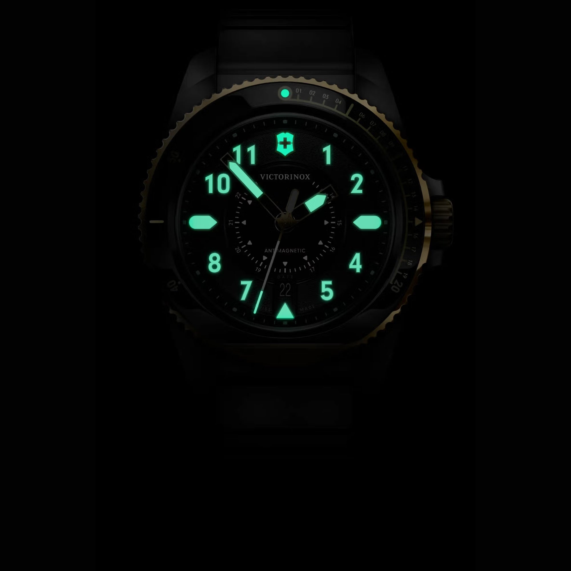 A dark close-up of a Victorinox Journey 1884 watch, featuring green glowing lume and a gold-toned bezel edge