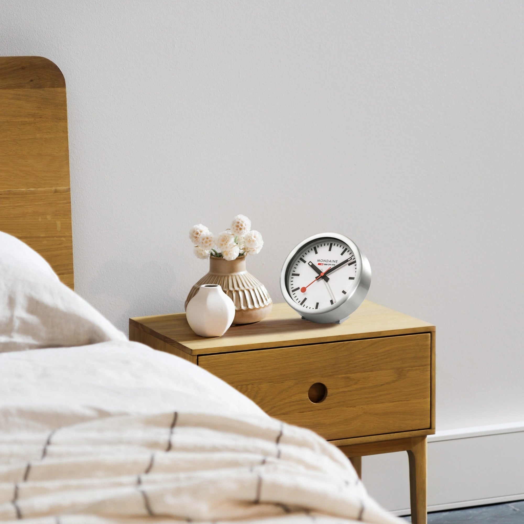 Mondaine Official Swiss Railways Alarm Clock A997.MCAL.16SBB.1 set on wooden side table