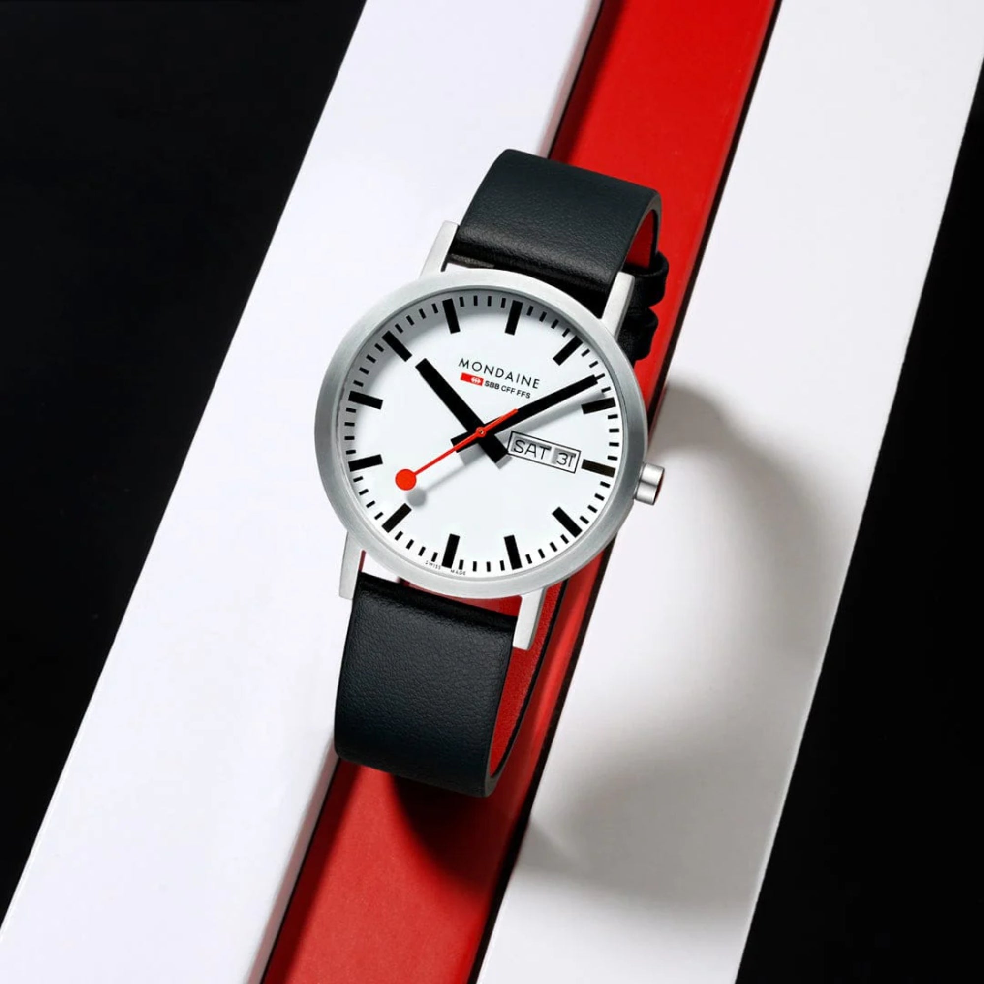Mondaine Classic A667.30360.11SBBV SBB railway watch positioned vertically on a red, white, and black geometric block display
