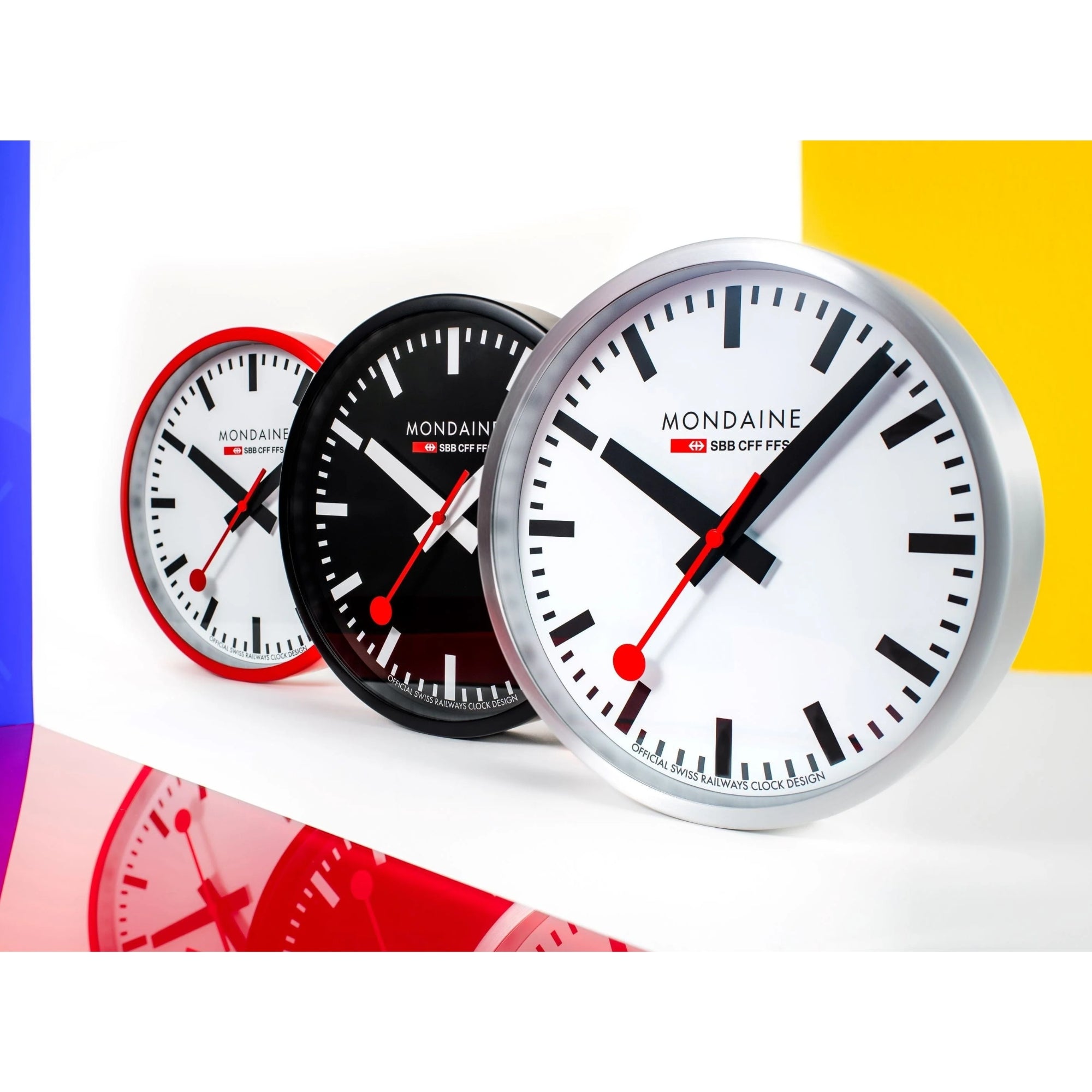 Mondaine Swiss Railways 25cm wall clocks lined up in silver, black, and red frames