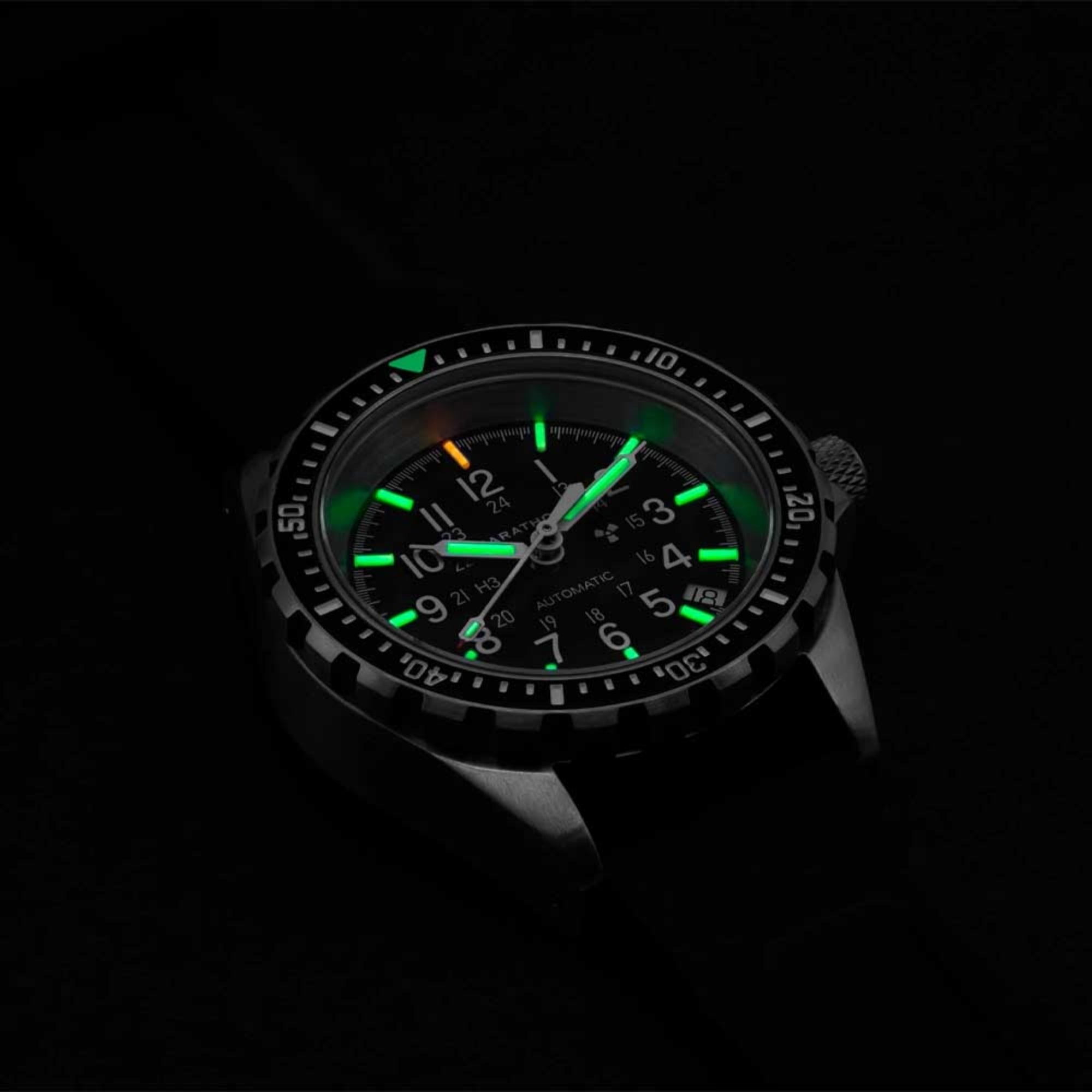 Marathon automatic diver’s watch luminous green dial in dark lighting with black rubber strap