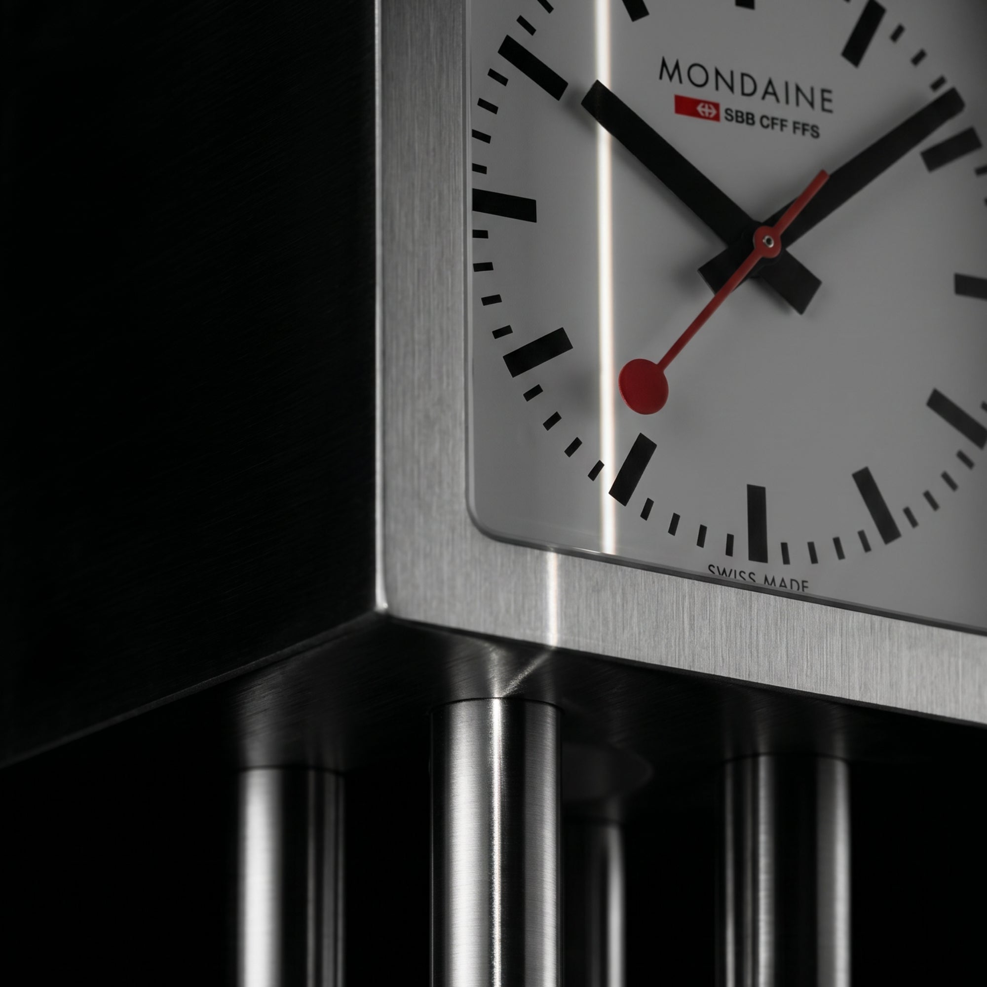 Aluminum table clock dial close-up with black markers and red second hand