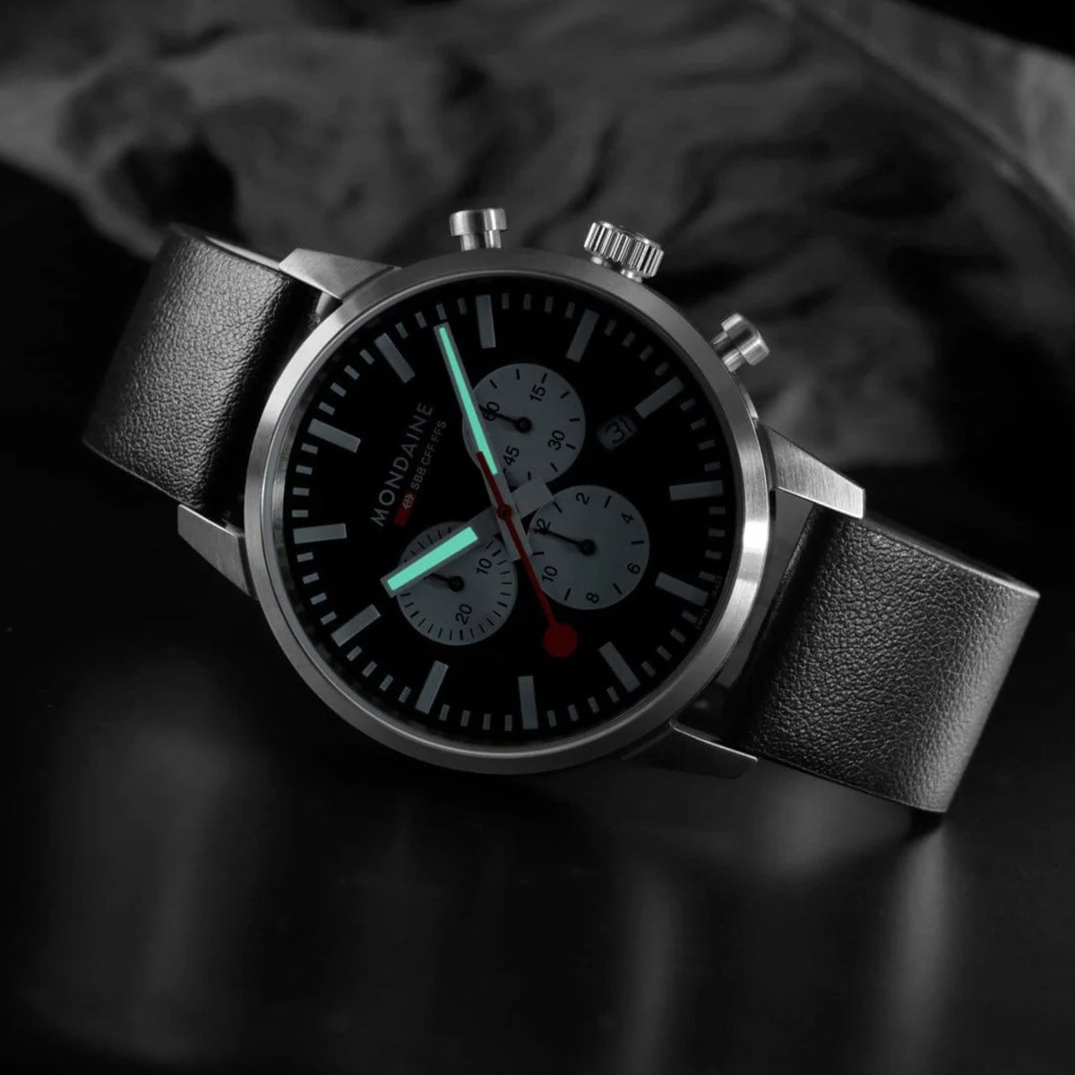 Mondaine Neo MSD.41420.LBV angled view showing luminous hands glowing on black dial