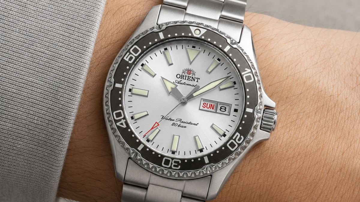 Orient Kamasu watch with a sunburst dial, luminescent markers, black bezel, and stainless steel bracelet on a wrist