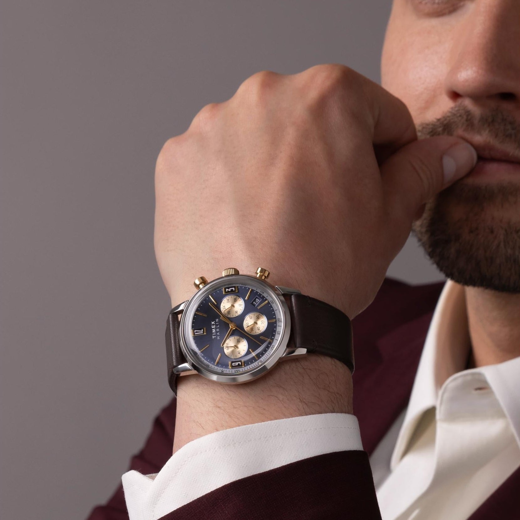 Timex chronograph on man's wrist, navy dial with subdials, brown leather strap