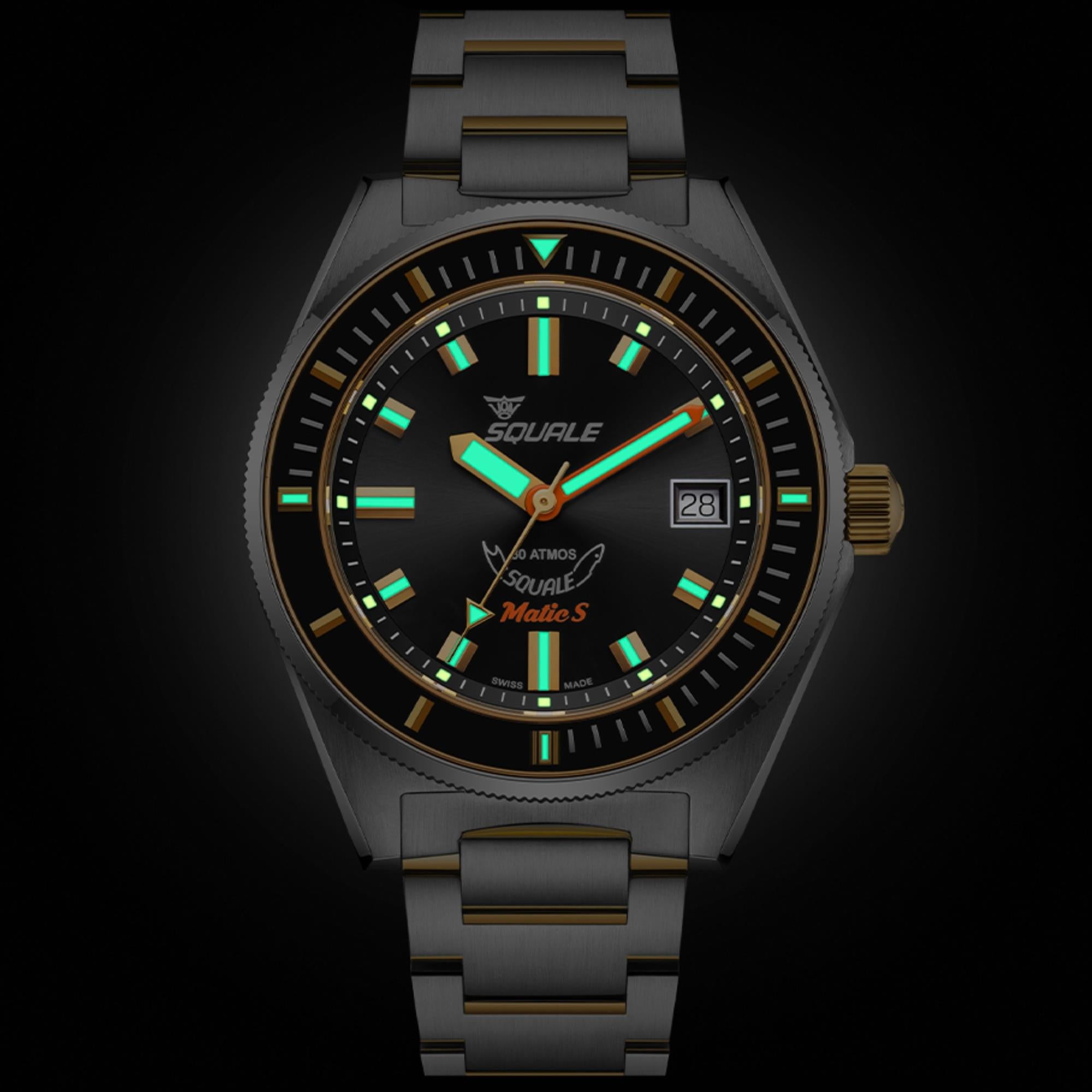 Steel automatic watch with black dial, green lume accents, gold markers, and date window