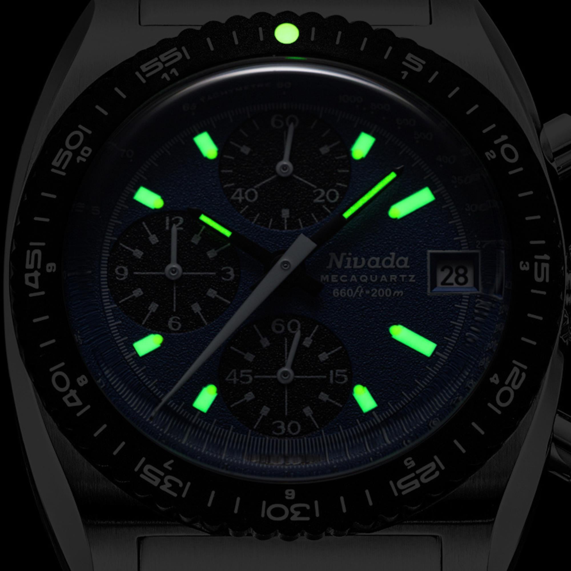 Quartz chronograph watch close-up with blue dial, glowing green markers, and date