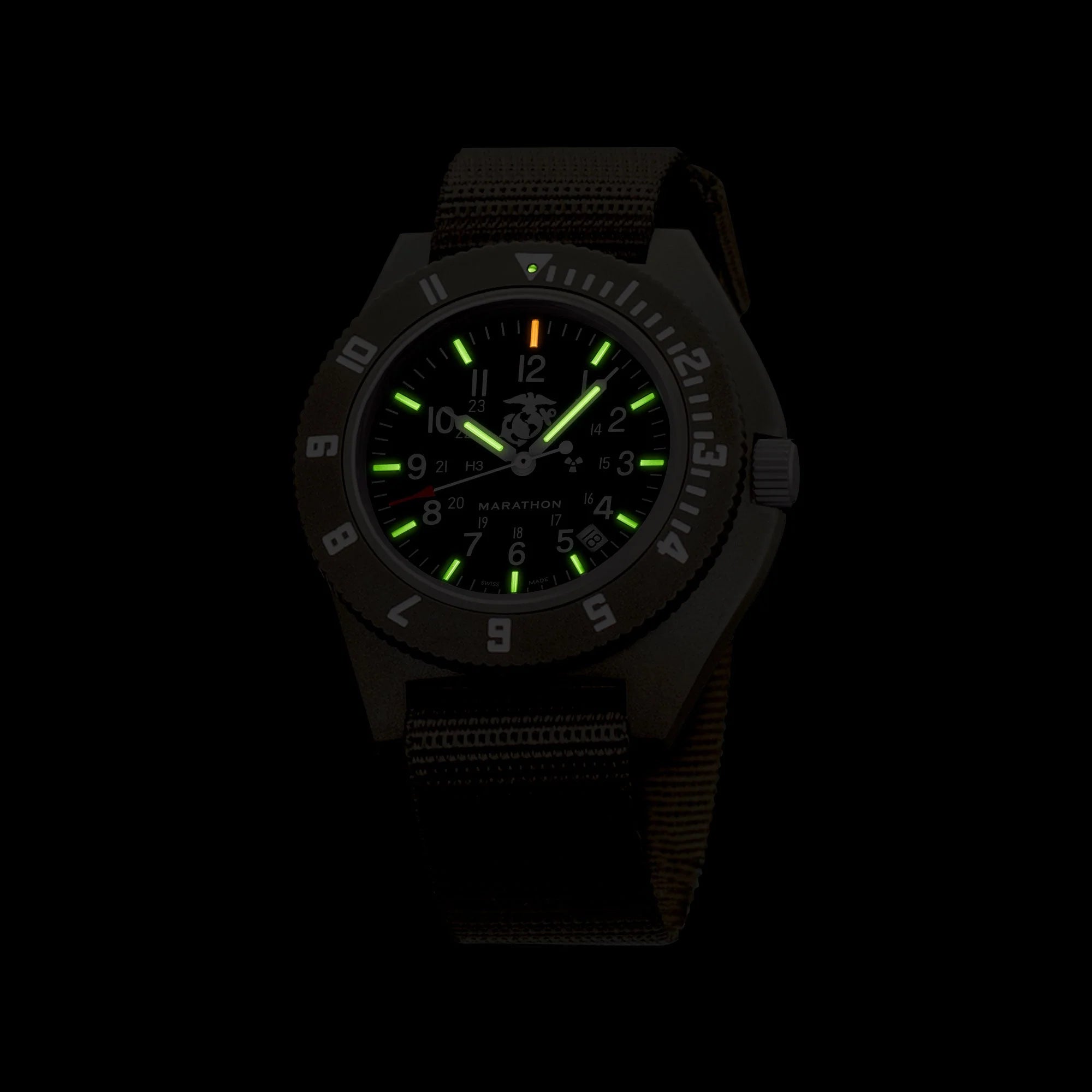 Marathon watch displaying glowing green tritium gas tubes on dial markers in darkness
